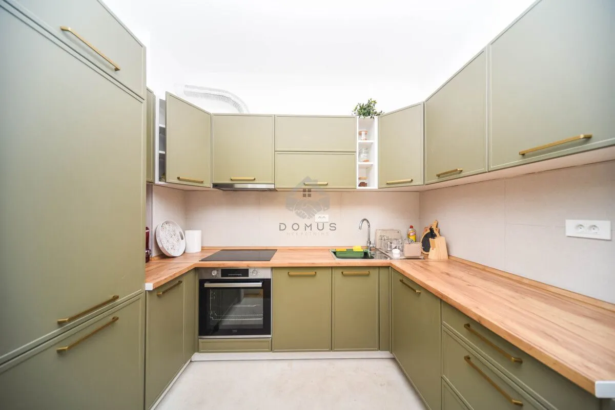 Kitchen with green cabinets and a wooden countertop.