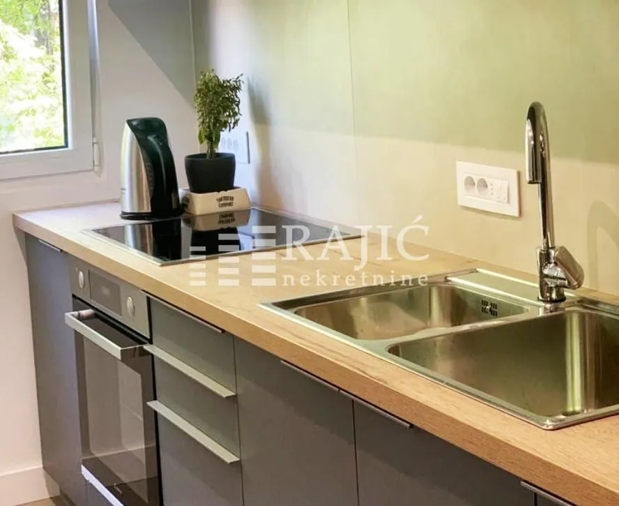 View of a modern kitchen with a wooden countertop and built-in appliances.