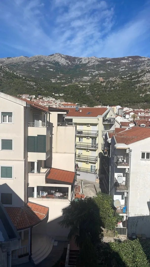 Pogled sa terase na okolne stambene zgrade i planine u pozadini.