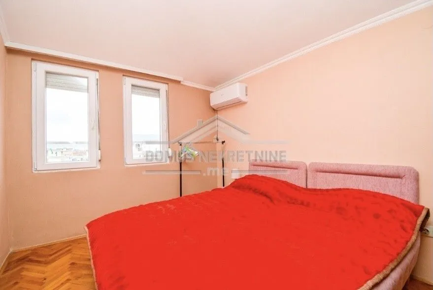 Simple bedroom featuring a double bed with a red cover.