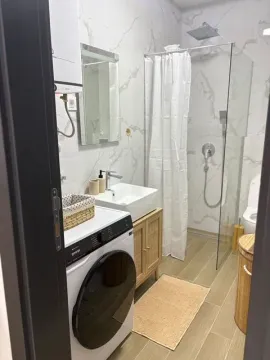 Savremeno opremljeno kupatilo sa tuš kabinom, umivaonikom i veš mašinom. - image 7