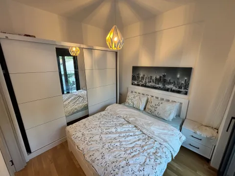 Uređena spavaća soba sa bračnim krevetom, velikim garderoberom sa ogledalom i modernim lusterom. - image 4