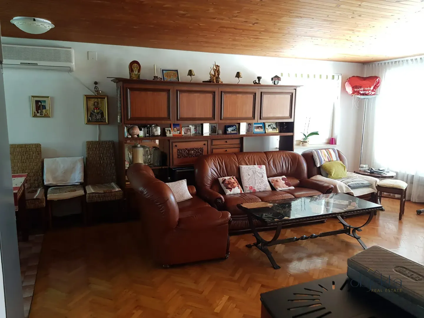 Dnevna soba sa garniturom od kože, drvenim namještajem i parketom.
