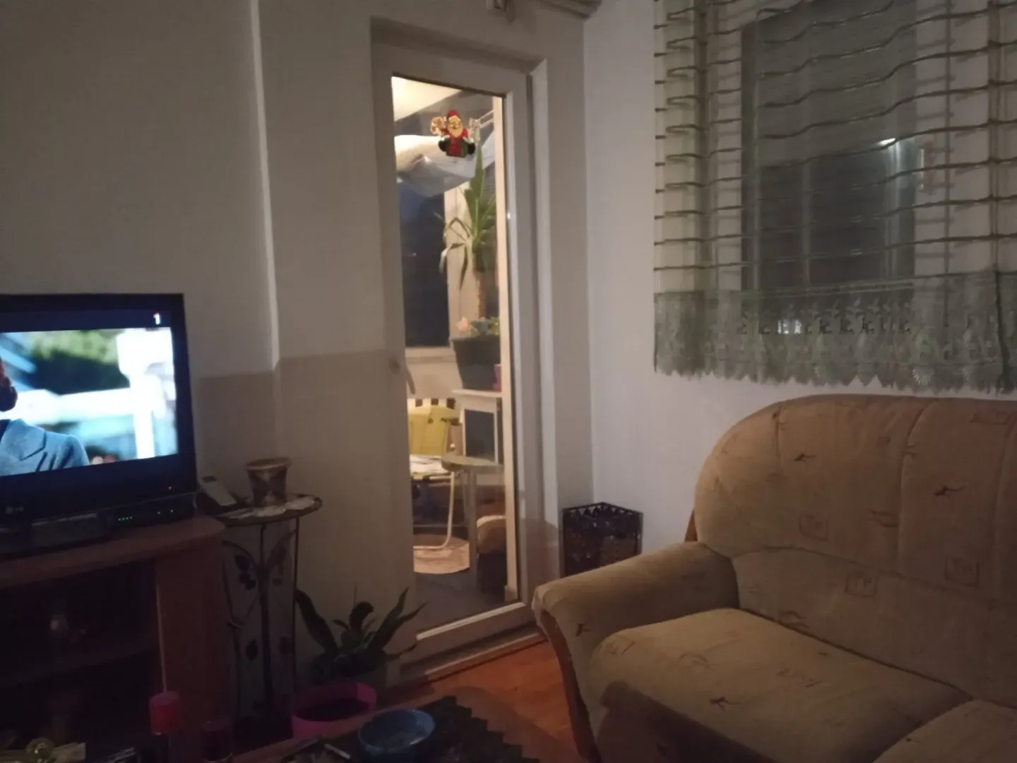 Dnevna soba sa televizorom i izlazom na balkon.