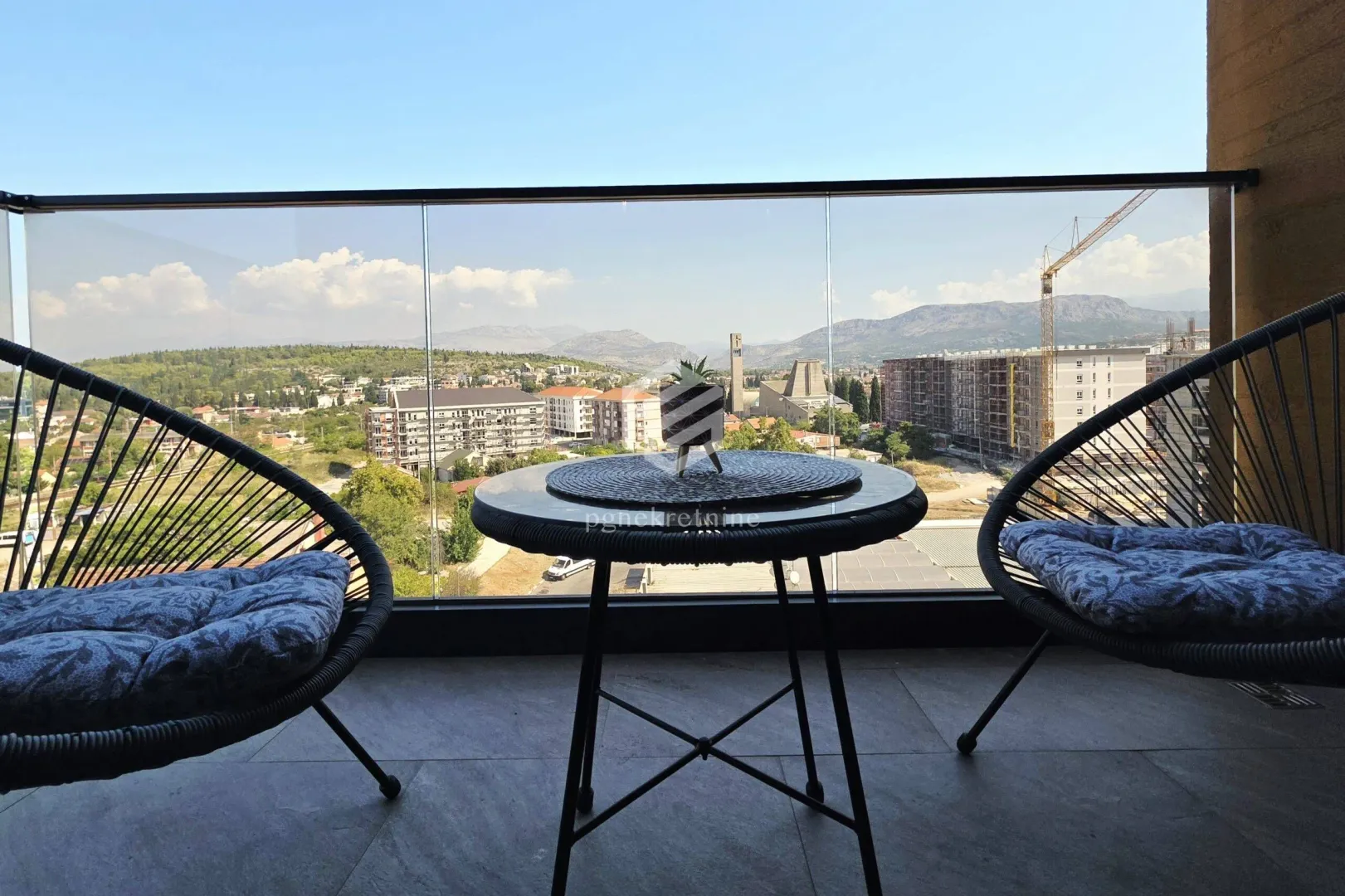Furnished balcony with a table, chairs, and an open view of the city.