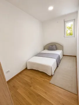 Jednostavna spavaća soba sa jednim krevetom i svijetlim zidovima. - image 3