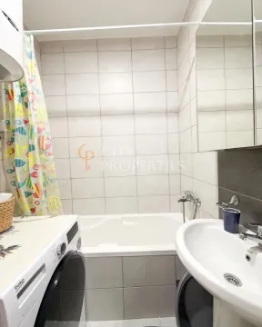 Bathroom equipped with a bathtub, washbasin, and washing machine. - image 5