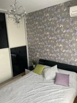 Bright bedroom featuring a double bed, decorative wallpaper, and a chandelier. - image 10