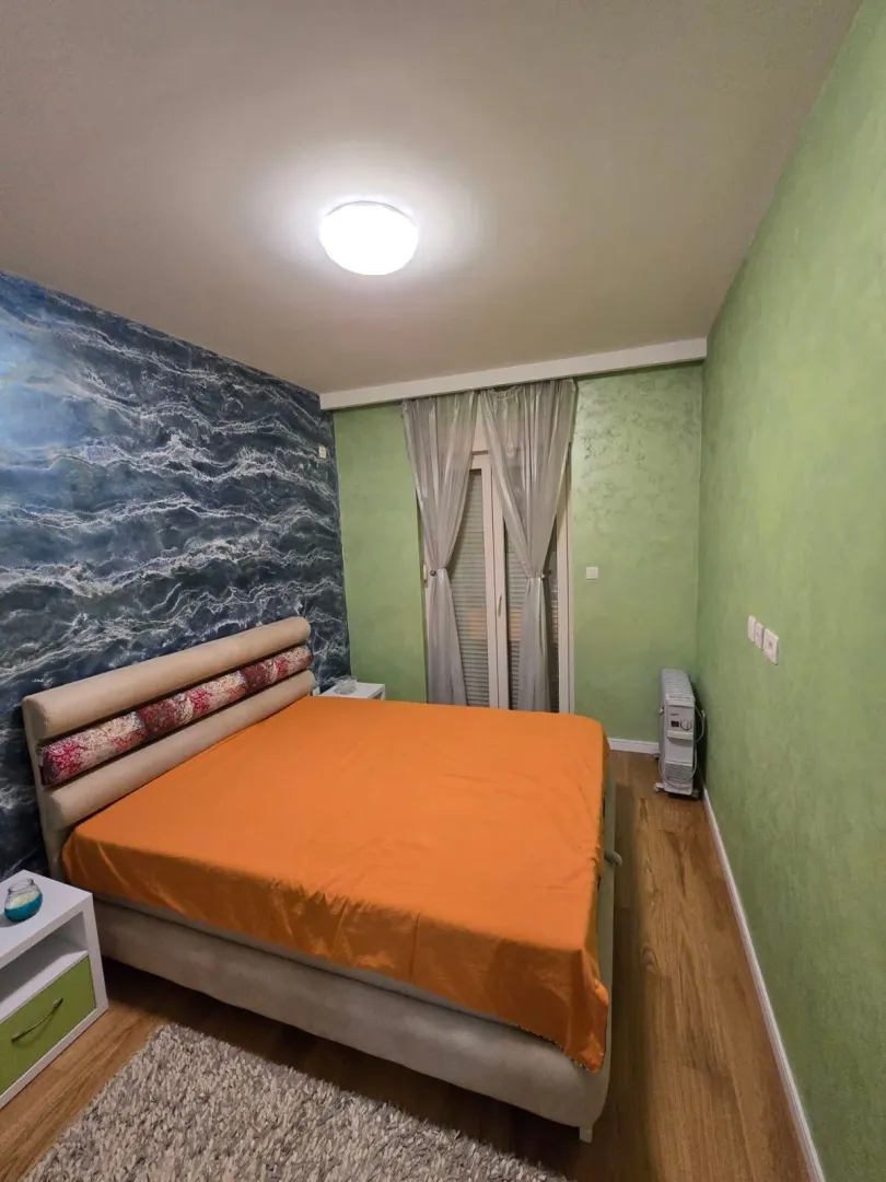 Spavaća soba sa bračnim krevetom i zelenim zidovima.