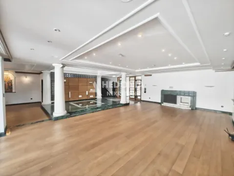 Spacious living room with wooden flooring, pillars, and a dropped ceiling with lighting. - image 3
