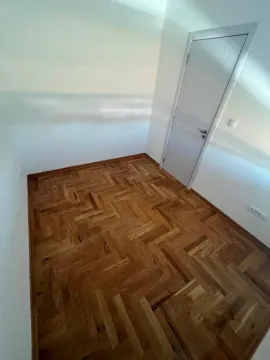Prazna soba sa drvenim parketom i belim vratima. - image 6