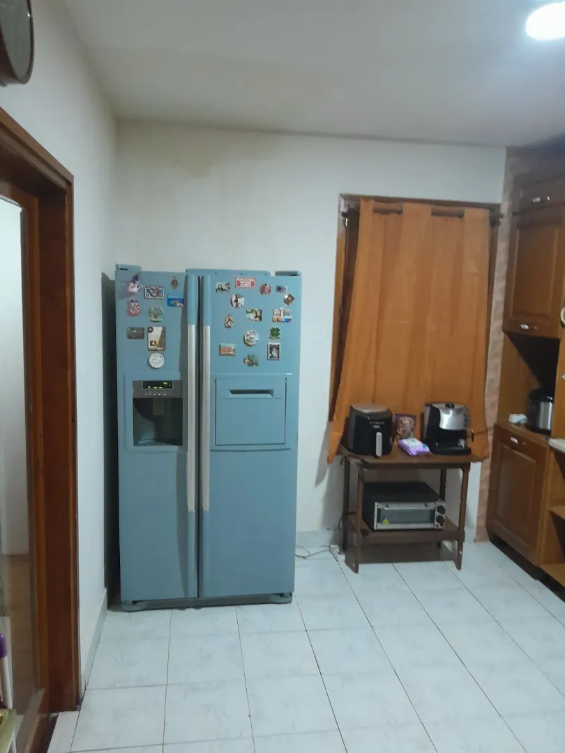 Kuhinja sa velikim plavim frižiderom i kuhinjskim elementima.