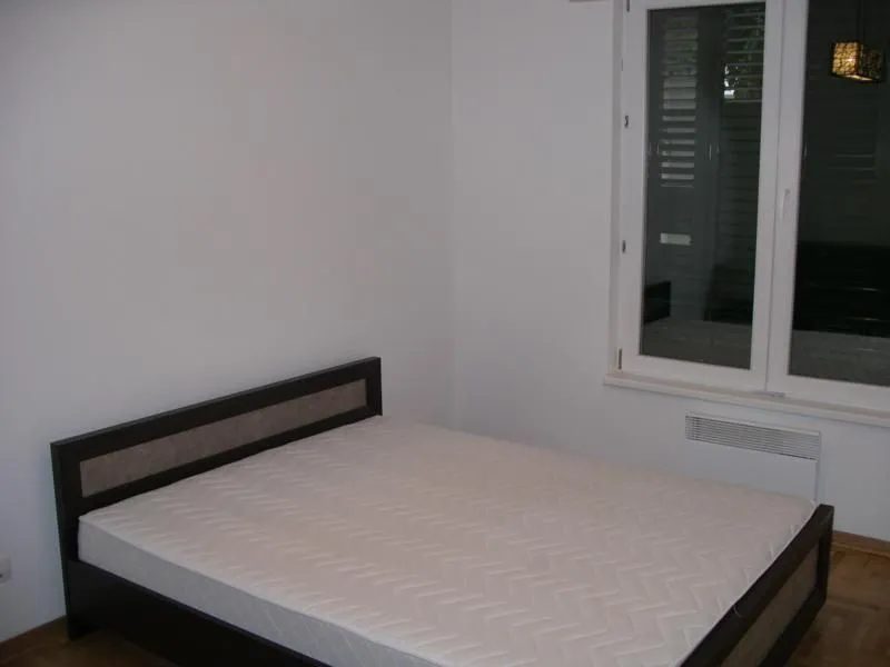 Jednostavna spavaća soba sa bračnim krevetom pored prozora.