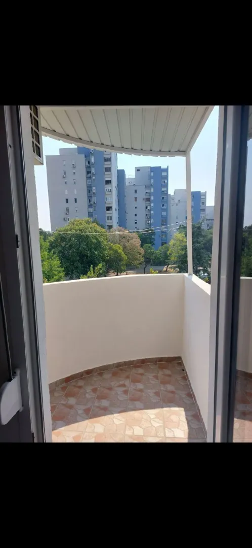 View from an open balcony towards surrounding residential buildings and greenery.