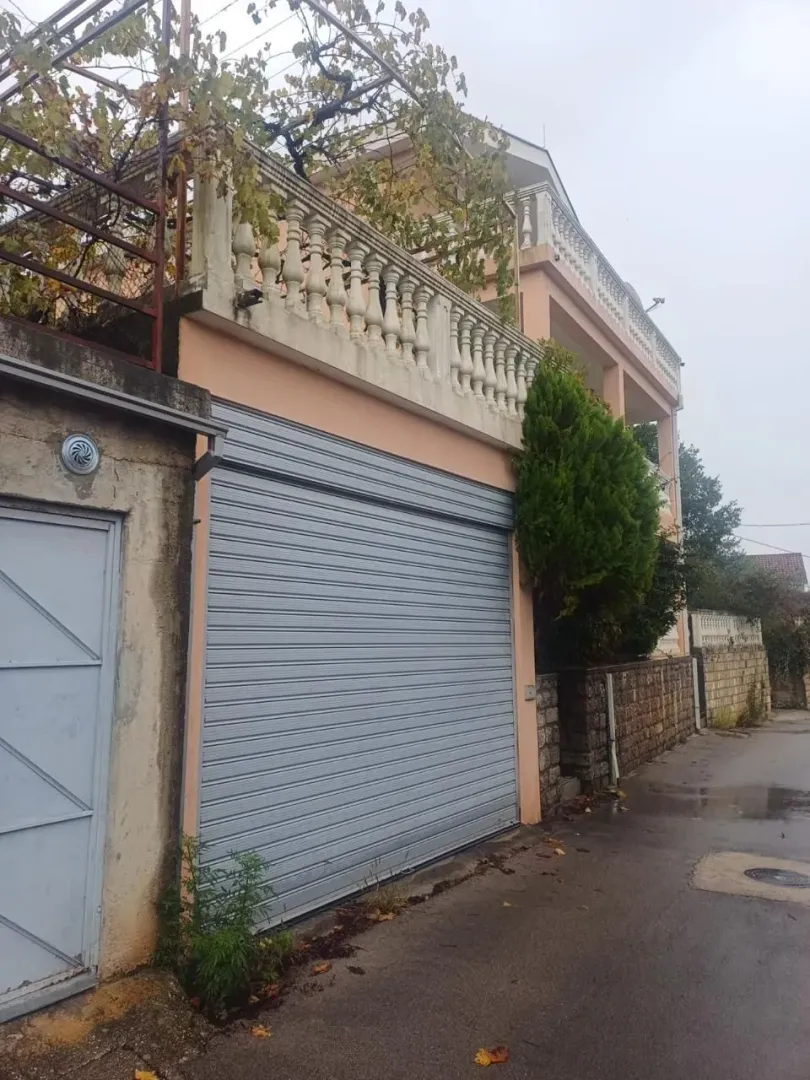 Spoljašnji pogled na kuću sa garažnim vratima i terasom.