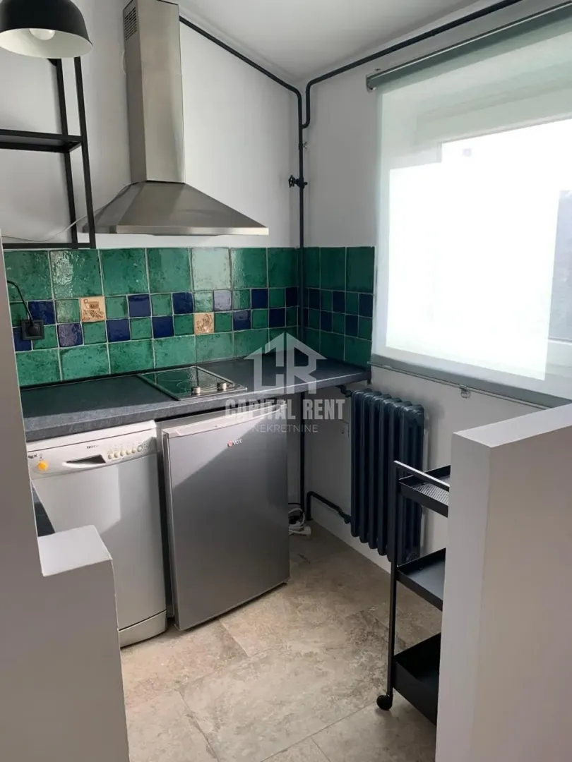 Small kitchen with green tiles, a stove, and a refrigerator.