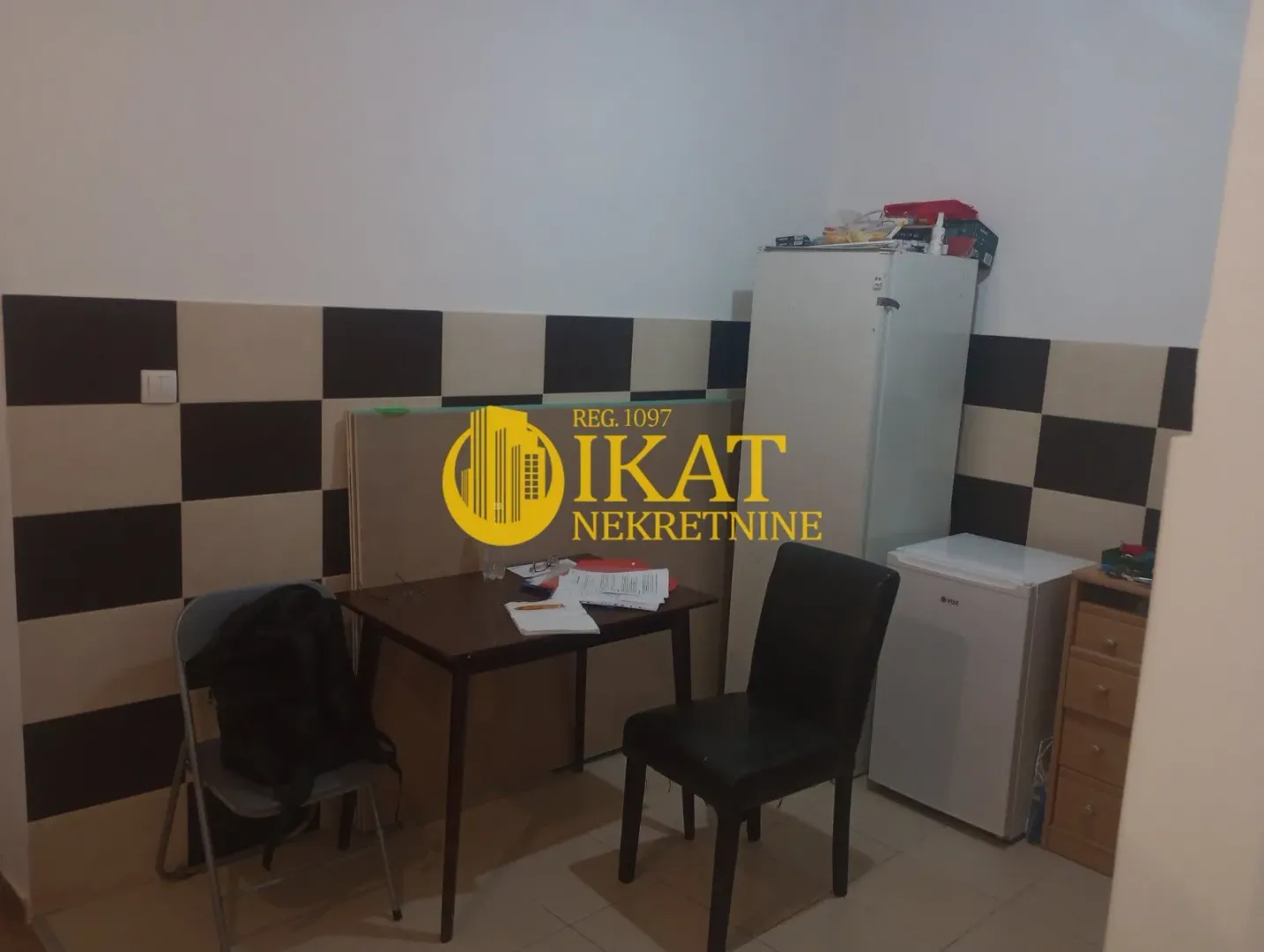 Smaller kitchen with refrigerators, dining table, and chairs.