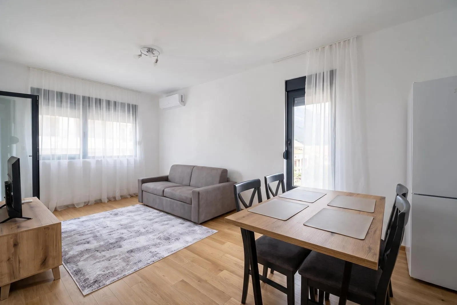 Living room with a sofa, dining table, and TV unit.