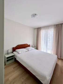 Bedroom with a double bed, bedside tables, and a window with curtains. - image 9