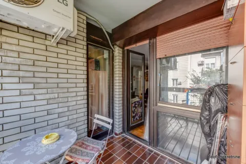 Covered balcony with a table, chairs, and an outdoor air conditioning unit. - image 20
