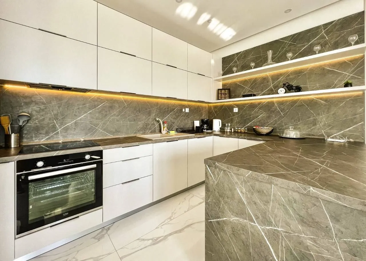 Modern kitchen with white cabinetry and grey marble countertops.