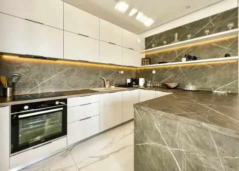 Modern kitchen with white cabinetry and grey marble countertops. - image 5