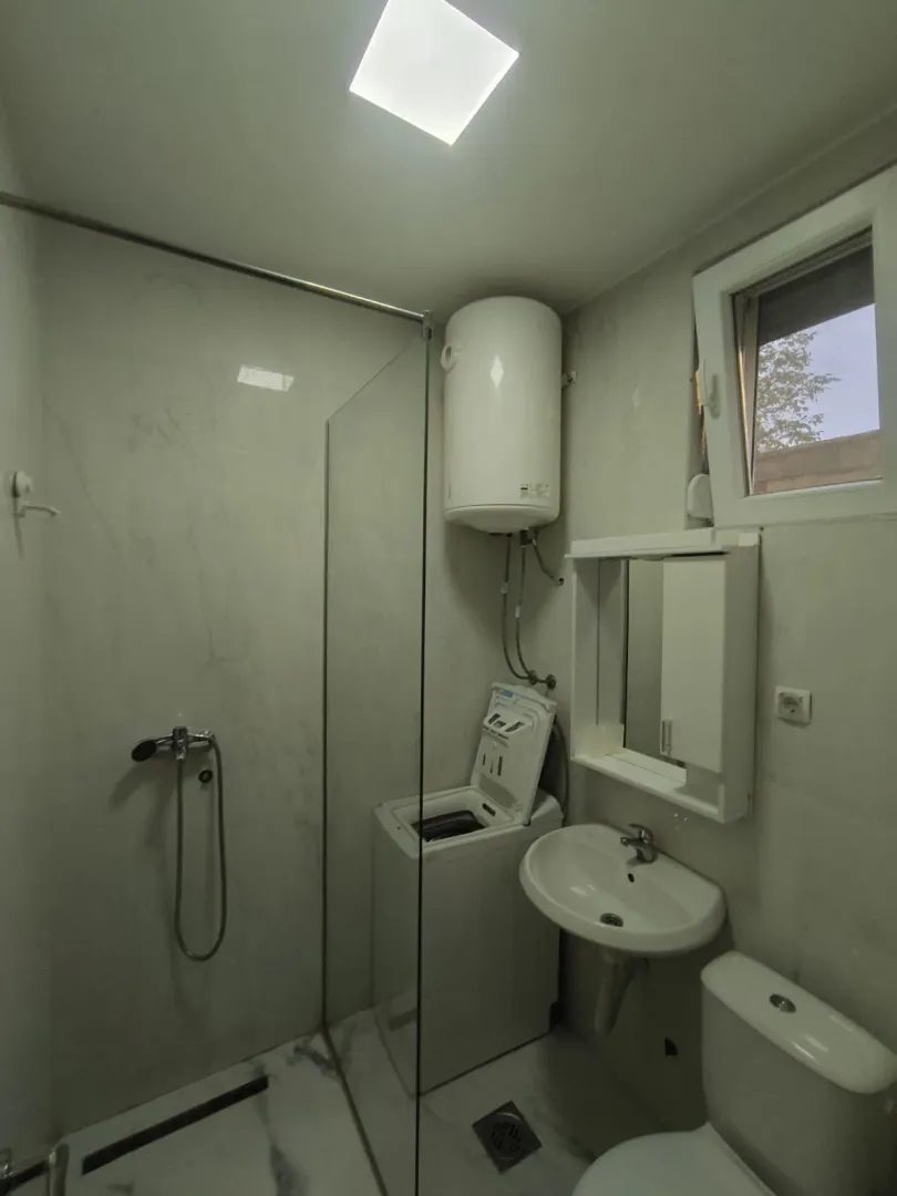 Bright bathroom with a shower cabin, washing machine, and boiler.