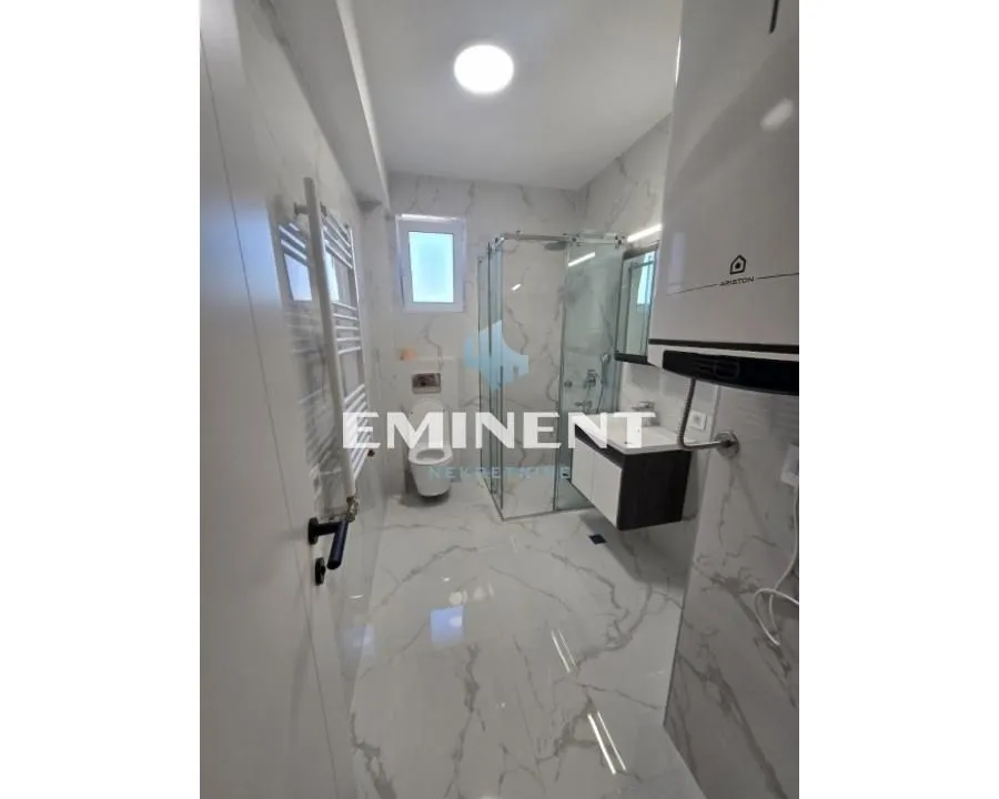 Modern bathroom with a shower cabin, washbasin, and toilet.