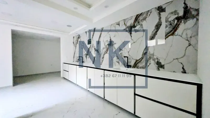 Modern kitchen with white cabinetry and a marble backsplash.