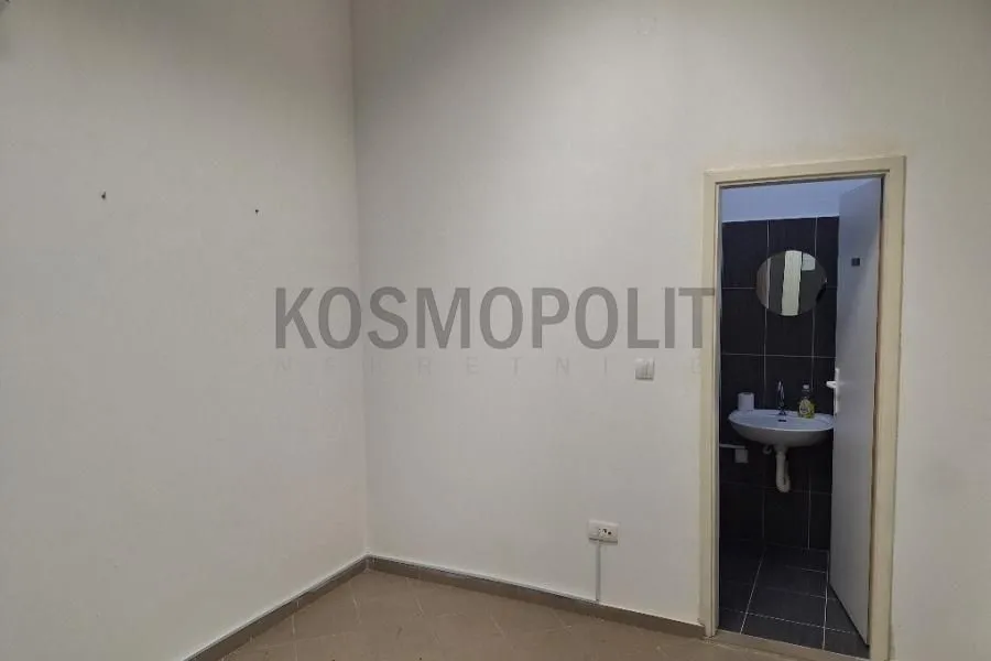 Empty room with a view of the bathroom through an open door.