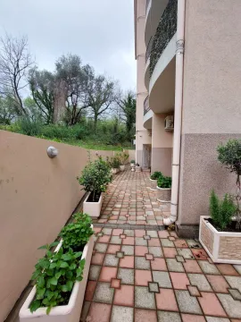 Popločani prolaz pored stambene zgrade sa saksijama biljaka. - image 16