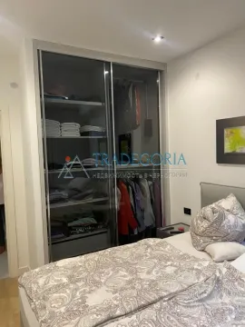 Spavaća soba sa velikim ugradnim garderoberom sa staklenim kliznim vratima i bračnim krevetom. - image 12