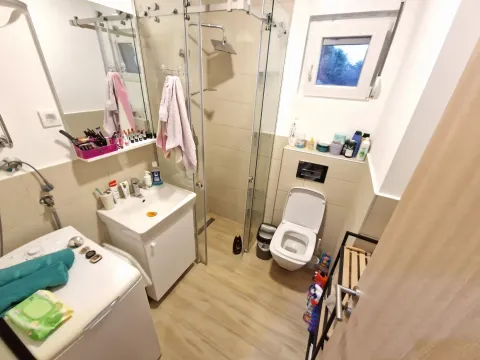 Bathroom equipped with a shower cabin, washbasin, toilet, and washing machine. - image 16