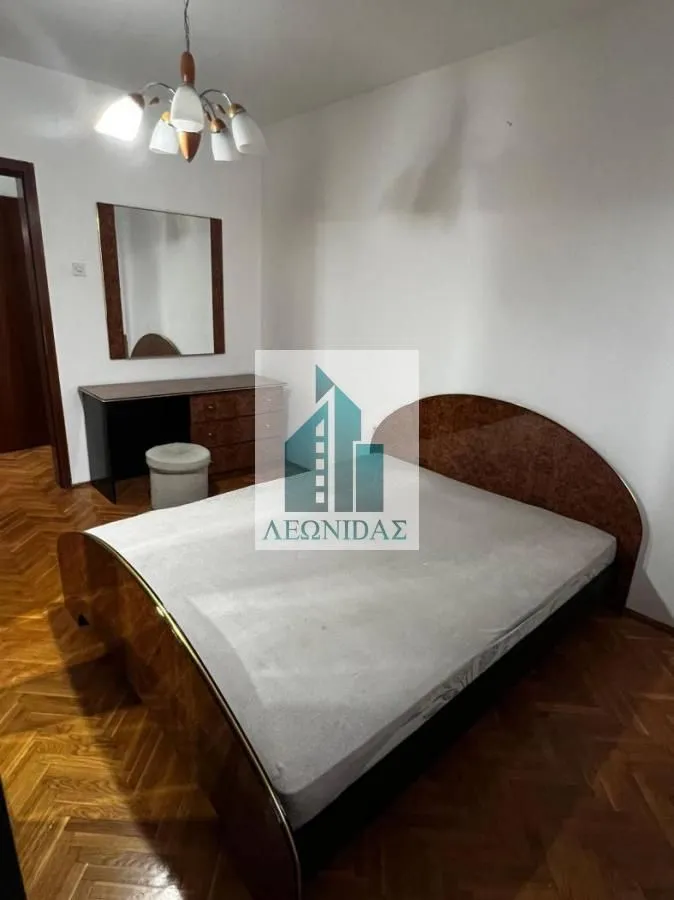 Furnished bedroom with a double bed, dresser, and mirror.