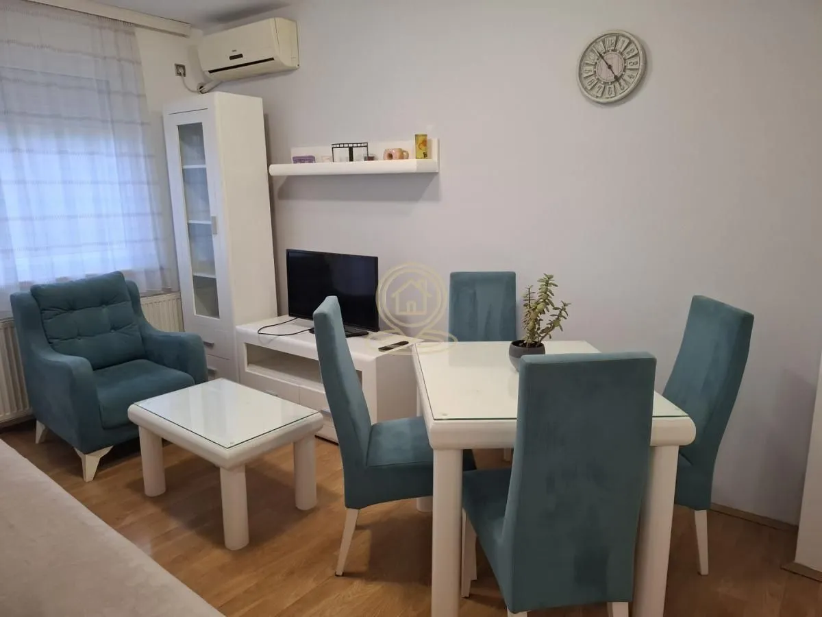 Dnevni boravak sa trpezarijskim stolom i plavim foteljama.