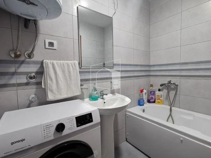Compactly equipped bathroom with a bathtub, washbasin and washing machine.