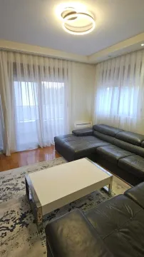 Dnevna soba sa garniturom, klub stočićem i velikim prozorima sa zavesama. - image 3