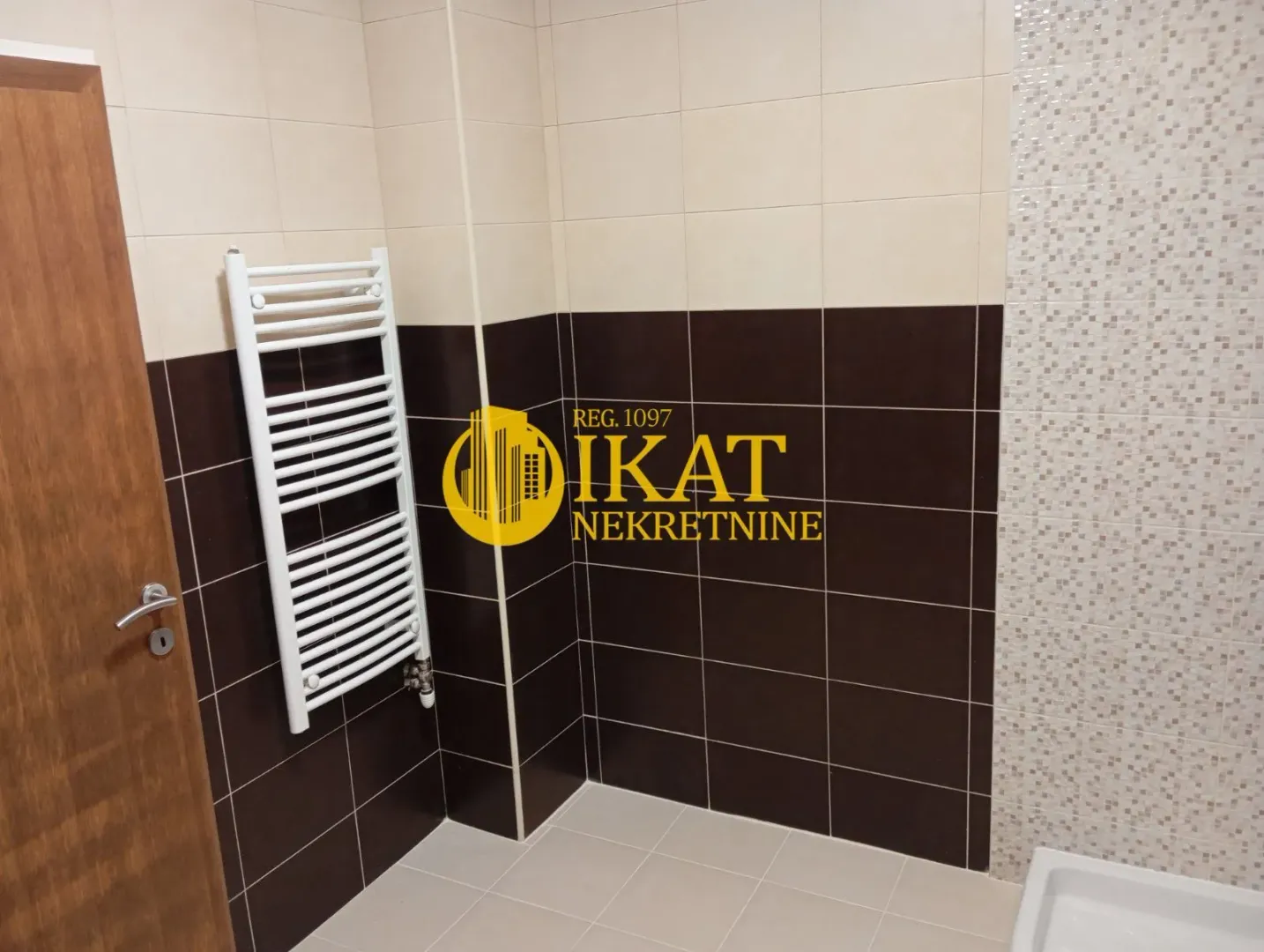 Bathroom with brown and beige tiles and a white radiator.