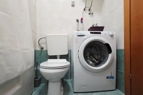 Small bathroom with a toilet and a washing machine. - image 7