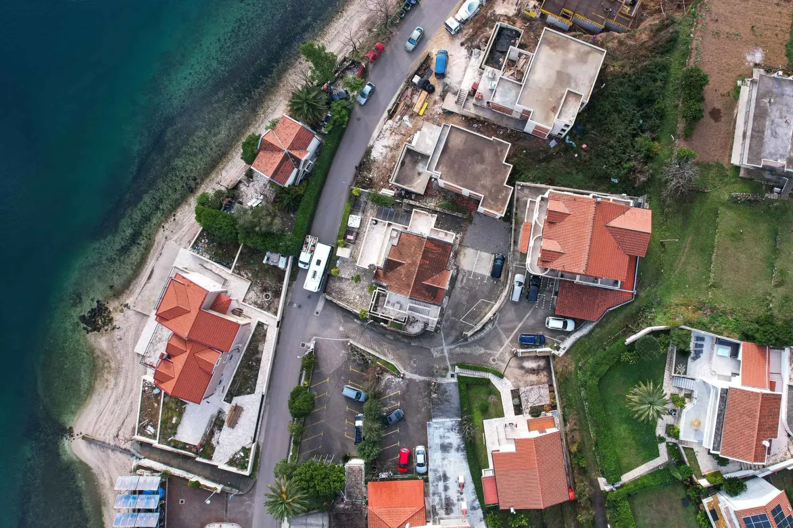 Pogled iz vazduha na priobalno naselje sa kućama i ulicom.