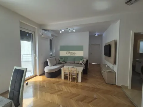Dnevni boravak sa garniturom za sedenje, televizorom i parketom na podu. - image 6