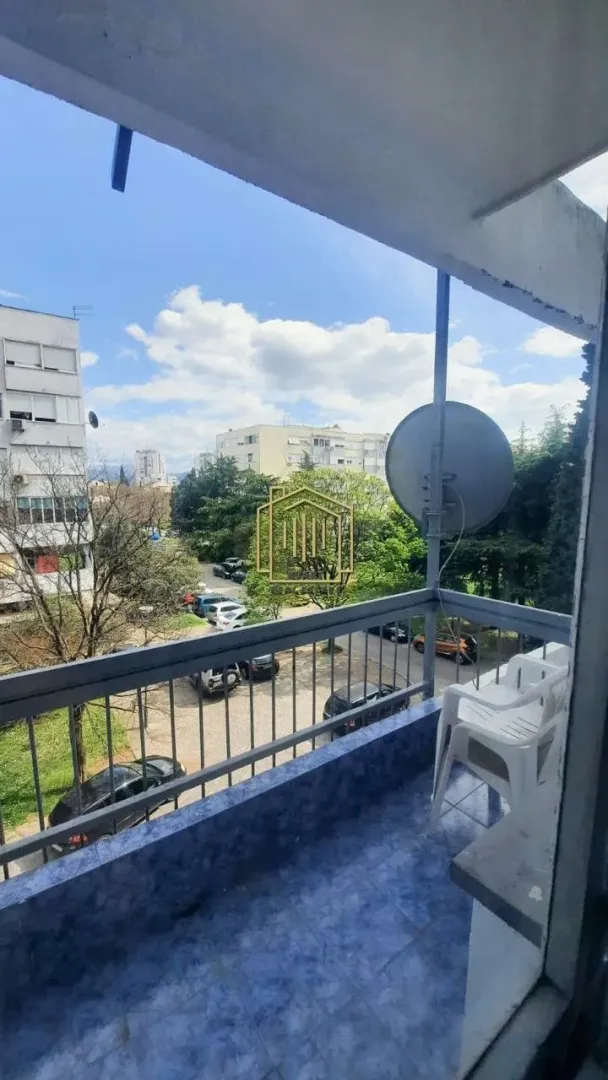 Manji balkon sa pogledom na okolne zgrade i zelene površine.