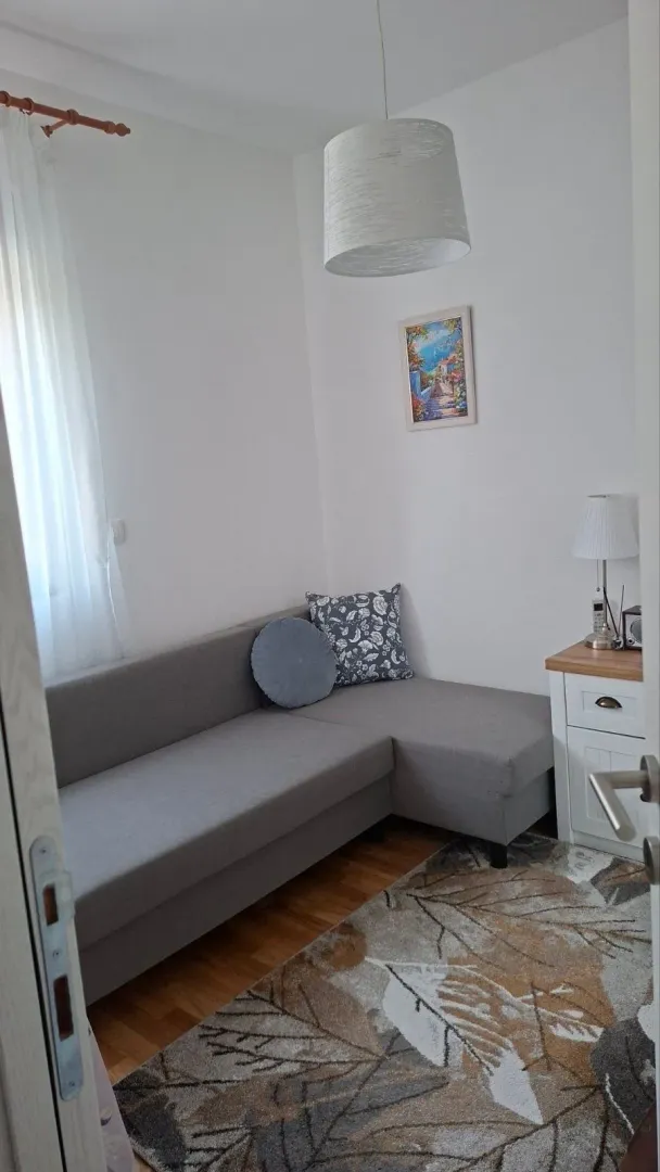 Dnevna soba sa ugaonom garniturom, tepihom i stočićem.