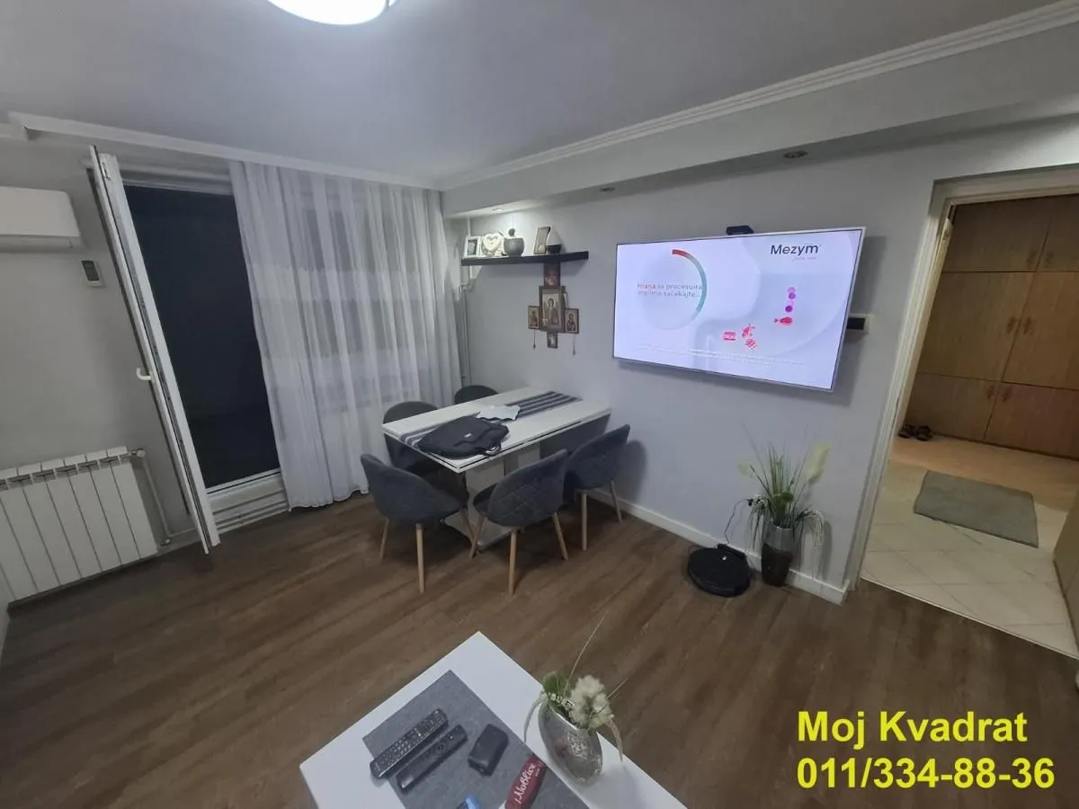 Dnevna soba sa trpezarijskim stolom i televizorom na zidu.