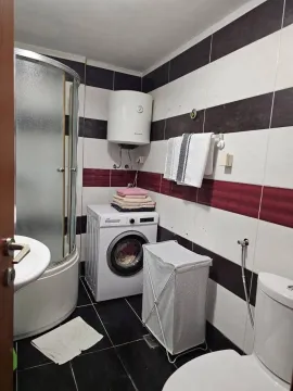 Small bathroom with a shower cabin, washing machine, and white and red tiles. - image 9
