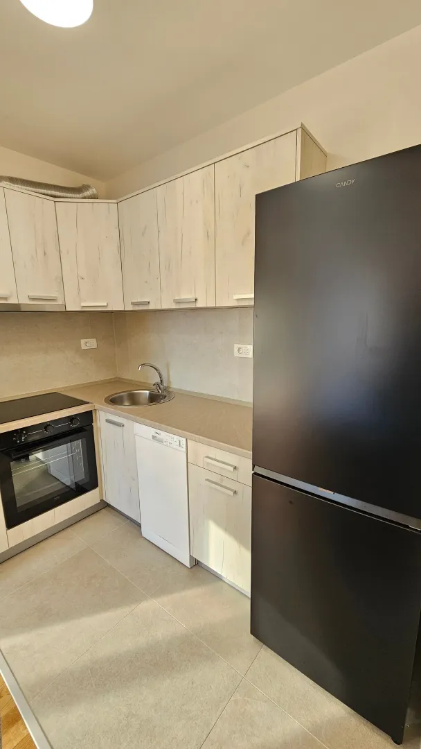 Small bright kitchen with built-in cabinetry and a black refrigerator.