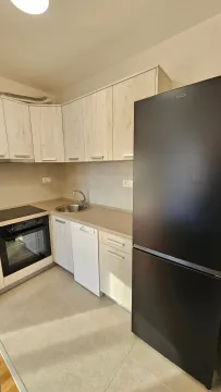Small bright kitchen with built-in cabinetry and a black refrigerator. - image 2
