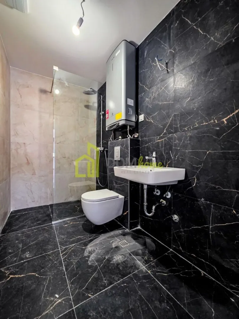 Modernly equipped bathroom with a walk-in shower, washbasin, and black marble tiles.