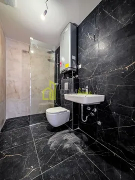 Modernly equipped bathroom with a walk-in shower, washbasin, and black marble tiles. - image 20