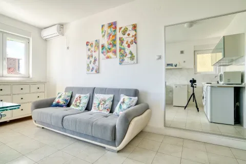 Living room with a grey sofa, decorative paintings, and an air conditioner. - image 5